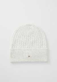 Bonnet en tricot blanc avec un motif texturé, présentant un revers côtelé et un petit accent métallique à l'avant. Matériau doux et flexible.