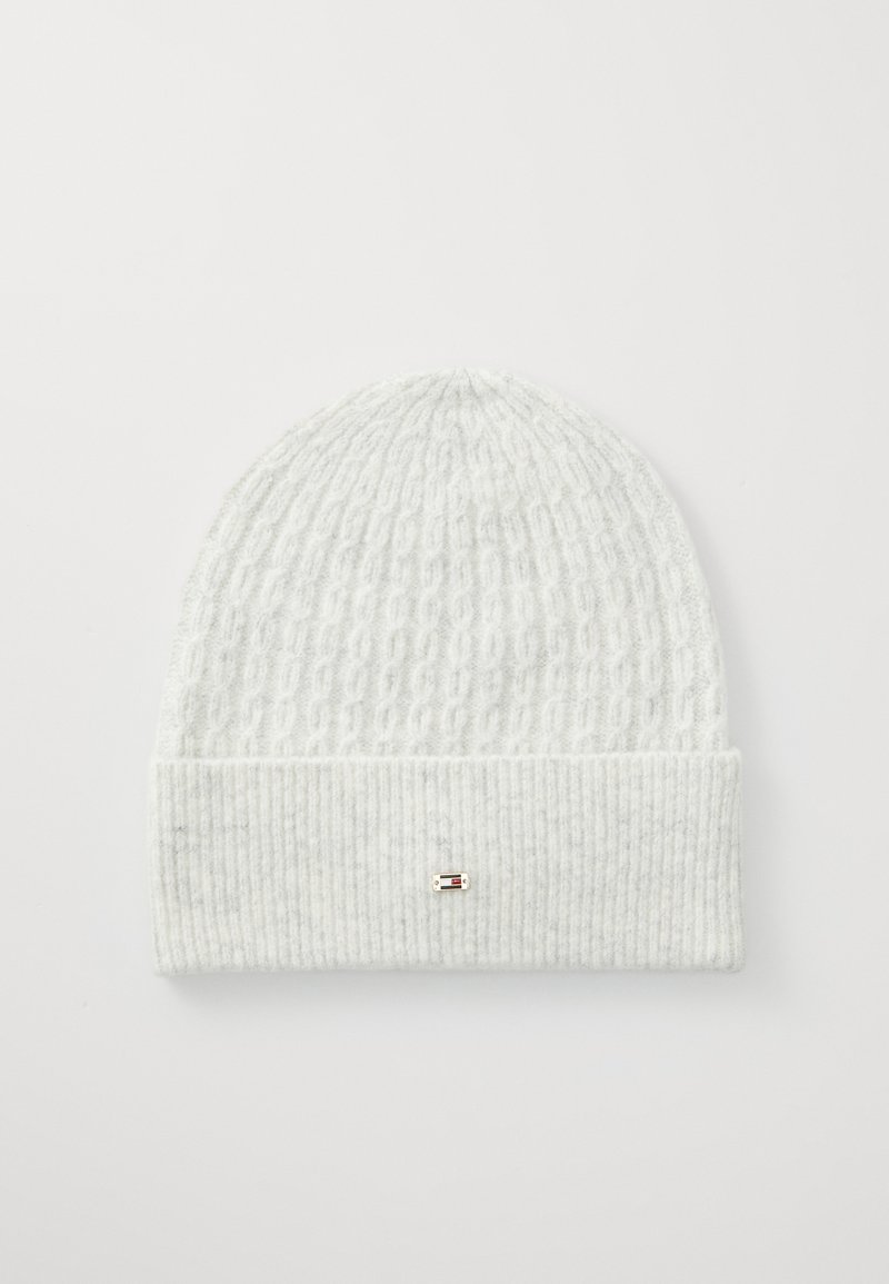 Bonnet en tricot blanc avec un motif texturé, présentant un revers côtelé et un petit accent métallique à l'avant. Matériau doux et flexible.