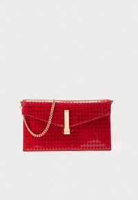 Pochette en cuir verni rouge avec découpes en forme de cœur, ferrures dorées, bandoulière chaîne et fermeture à clapet rectangulaire.