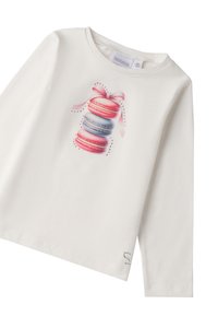 Camicia bianca a maniche lunghe con stampa di macarons colorati e un nastro rosa. Tessuto in cotone morbido con vestibilità rilassata e orlo cucito.