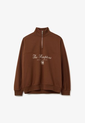 Bruine kwart-ritssweater met de tekst "The Hamptons" en "East End of Long Island" en een wapenschild in het wit op de voorkant gedrukt.