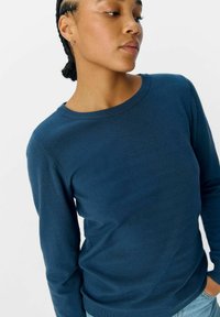 Pull en tricot bleu marine avec un col rond et des manches longues, présentant une texture lisse et une coupe ajustée.