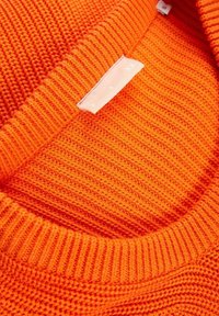 Jasnopomarańczowy sweter dzianinowy o prążkowanej strukturze. Posiada okrągły kołnierzyk oraz niewielką metkę na dekolcie.
