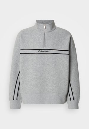 Γκρι φούτερ με φερμουάρ και ψηλό γιακά. Διαθέτει μαύρες ρίγες και λογότυπο στο στήθος. Μαλακό, υφασμένο ύφασμα. Καθημερινό σχέδιο.