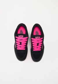 Musta mokkanahkakengät kirkkaan vaaleanpunaisilla nauhoilla ja sisäpohjilla. Tässä on sileä, pyöreä kärki ja kontrastiväri brändäys kengän kielekkeessä.