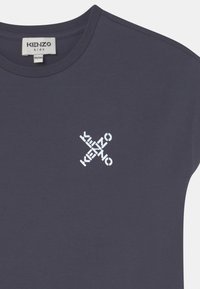 T-shirt pour enfants bleu fonc�é à col rond, avec un logo "KENZO" blanc croisé sur la poitrine et une étiquette de taille à l'intérieur du col.