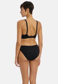 Svart bikini-set i ett enfärgat svart, texturerat tyg. Toppen har justerbara axelband och en krokstängning; botten har en hög midja.