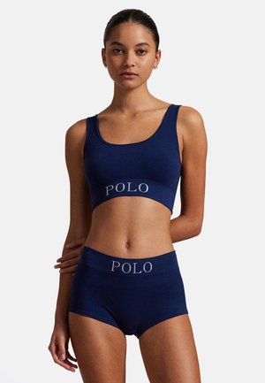 Tmavě modrý žebrovaný bralet a k němu ladící vysoké šortky s kontrastním logem "POLO". Měkká látka s přiléhavým střihem a jednoduchým designem.