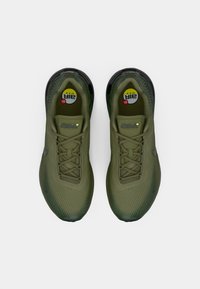 Olivovo zelené športové topánky s sieťovaným zvrškom, zaokrúhlenou špičkou, textúrovaným povrchom a viditeľným vzduchovým tlmením v čiernej podrážke. Šnúrky sú pletené.
