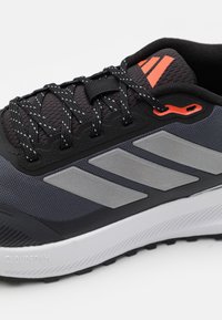 Baskets noires de sport avec une tige texturée, des accents gris et des détails réfléchissants. Dispose d'une semelle Cloudfoam et d'un design léger.
