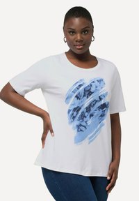 Witte t-shirt met korte mouwen en een blauwe abstracte bloemenprint. Zachte stof, ronde halslijn en een licht uitlopende onderrand.