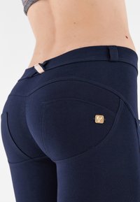 Leggings blu navy realizzati in tessuto morbido, con un design aderente, tasche posteriori curve e un piccolo logo accentato su una tasca.