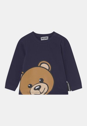 Mørkeblå babyt-shirt med lange ærmer, prydet med et stort smilende bjørneansigt og Moschino mærkeetiket på siden.