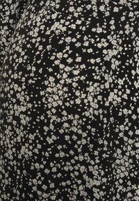 Tecido preto com uma estampa floral apresentando pequenas flores brancas espalhadas. A textura parece suave, com um design leve e macio.