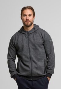 Felpa grigia con zip realizzata in tessuto testurizzato, dotata di cappuccio, tasca con zip e polsi neri a contrasto. Design liscio e funzionale.
