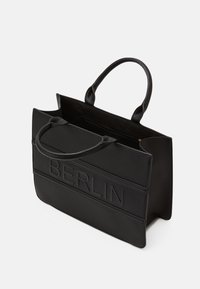 Sac fourre-tout noir en matériau texturé, avec des poignées doubles, une ouverture en haut et le mot "BERLIN" en relief sur le devant.