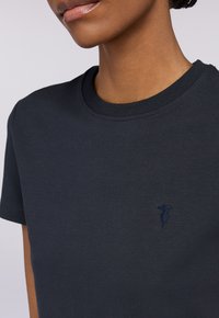 Tmavě modré tričko vyrobené z měkké bavlny, s klasickým kulatým výstřihem a krátkými rukávy, s malým vyšitým logem na hrudi.