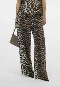 Pantalons larges en imprimé léopard marron et noir, en tissu texturé, avec un haut assorti et un petit sac à main.