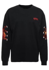 Mustat pitkät hihat -t-paita, jossa on punaiset brodeeratut tiikerin kynnet molemmilla hihoilla ja pieni punainen teksti kuvio rinnassa.