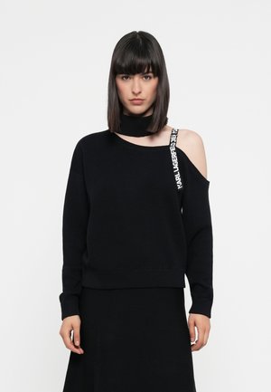 Black sweater with an asymmetrical neckline and long sleeves, featuring one shoulder exposed and a branded strap across the shoulder.
