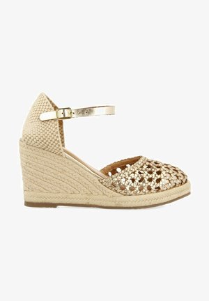 Chaussure espadrille à talon compensé avec une tige tressée en or métallique, une semelle intermédiaire en jute beige tressé et une bride de cheville ajustable.