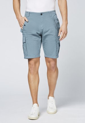 Blue cargo shorts featuring multiple side pockets, a front button closure, and a relaxed fit, paired with white sneakers.