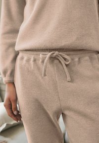 Beige texturerad lounge-set bestående av ribbad tyg, avslappnad passform, elastisk midja med dragsko och långa ärmar.