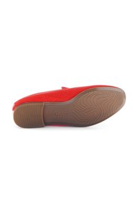 Rote Netzschlupfschuhe mit einer strukturierten braunen Gummisohle, die über einen leichten Absatz und ein eingeprägtes Logo auf der Sohle verfügt.