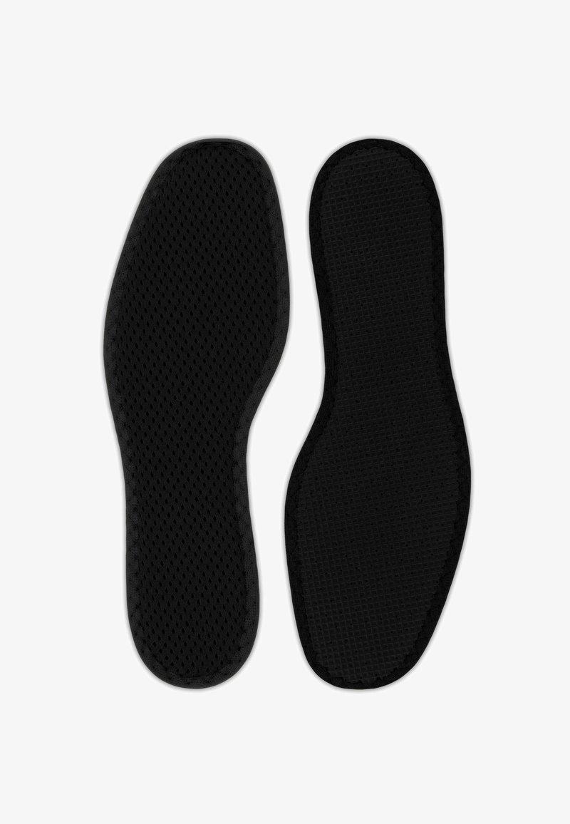 Paire de semelles de chaussures noires avec surfaces texturées, l'une montrant le dessus avec un maillage respirant, l'autre montrant le dessous à motifs.