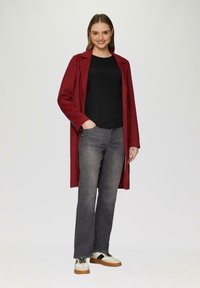 Rode wollen blend jas met een lange silhouette, zwart shirt, grijze jeans en beige sneakers met zwarte accenten. Gladde textuur, op maat gemaakt ontwerp.