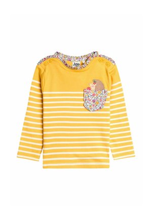 Das gelbe Langarmshirt hat weiße horizontale Streifen, einen Blumen-Kragenbesatz und ein Igel-Motiv auf einer gemusterten Tasche.