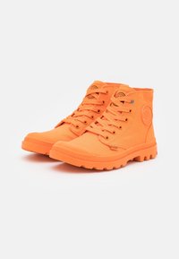 Zapatillas altas de lona de color naranja brillante con suelas de goma a juego, que presentan un parche de logo redondo, cordones y detalles texturizados.