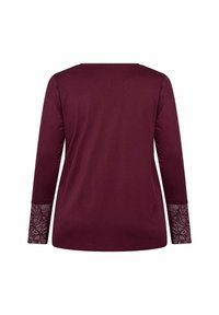 Haut bordeaux à manches longues avec des accents en dentelle aux poignets. Tissu doux, coupe décontractée et col rond. Vue arrière seulement.
