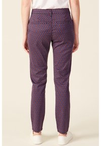 Colorful patterned trousers featuring a geometric design in blue and red, slim fit, with two back pockets, and a smooth fabric texture.