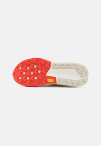 Schuhsohle mit einem roten Gummi-Profilmuster und beigen Abschnitten. Verfügt über ein Vibram-Logo, eine strukturierte Oberfläche für besseren Grip und ein leichtes Design.