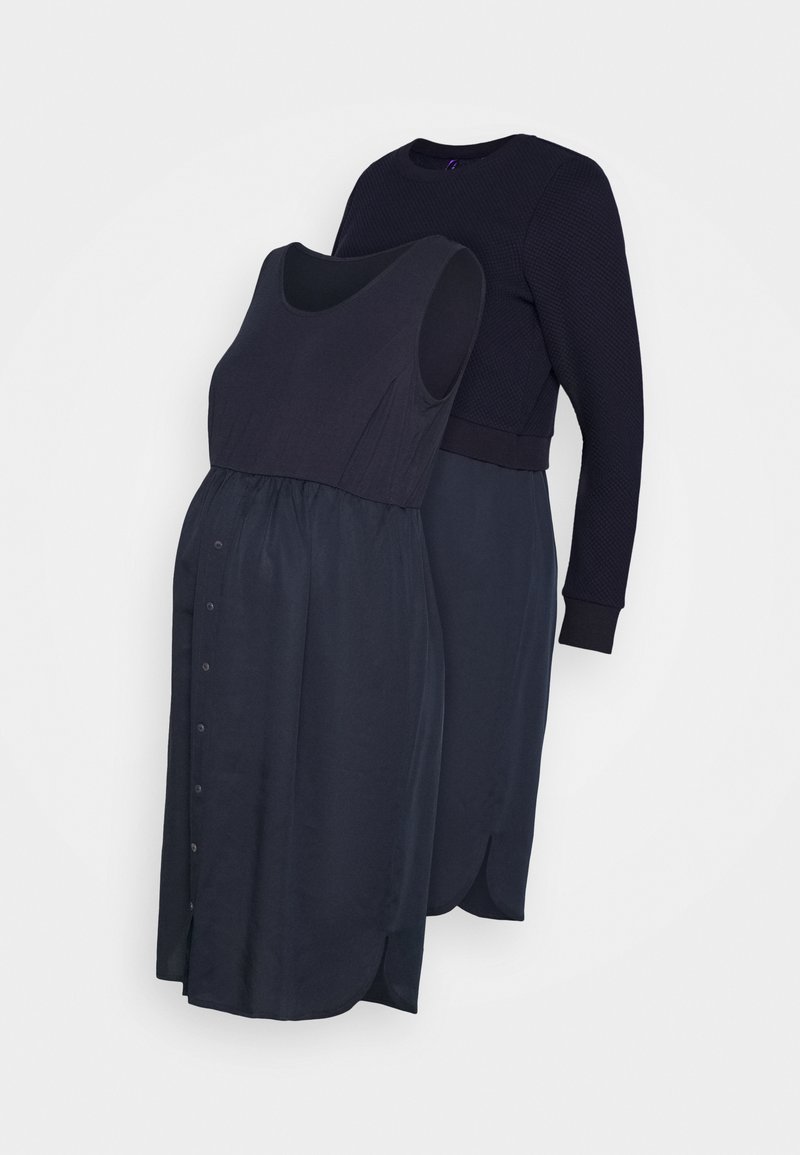 To-delt graviditetsoutfit i mørkeblå: en ærmeløs kjole med samlet talje og knapdetaljer, lagdelt med en tekstureret bluse med lange ærmer.