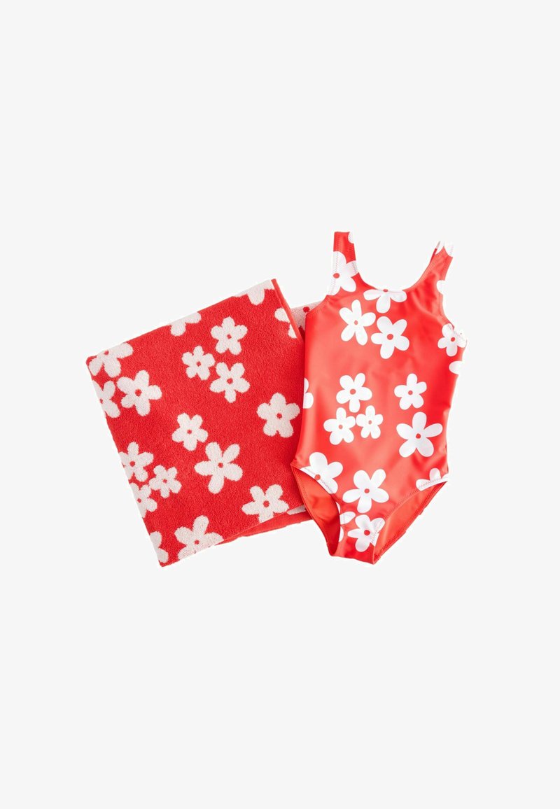 Roter Einteiler-Badeanzug und Handtuch-Set mit großen weißen Blumenmustern, flach auf weißem Hintergrund gelegt.