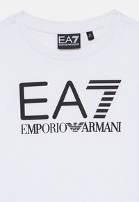 Valge puuvillane T-särk, millel on must graafiline kujundus koos "EA7 EMPORIO ARMANI" tekstiga ja logoga. Ümar kaelus ja lühikesed varrukad.