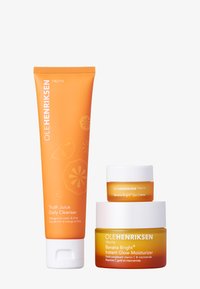 OLEHENRIKSEN skincare set featuring an orange tube of Truth Juice Daily Cleanser, a yellow eye cream, and a yellow moisturizer. Textured packaging.