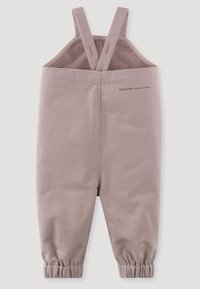 Mamelucos de color rosa claro con tirantes ajustables, puños elásticos en los tobillos y una tela suave, ligeramente texturizada para un ajuste ceñido.