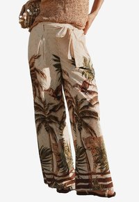 Pantalons larges en tissu léger, avec une base beige orn�ée de motifs de palmiers et de léopards. Liens à la taille et texture perforée.