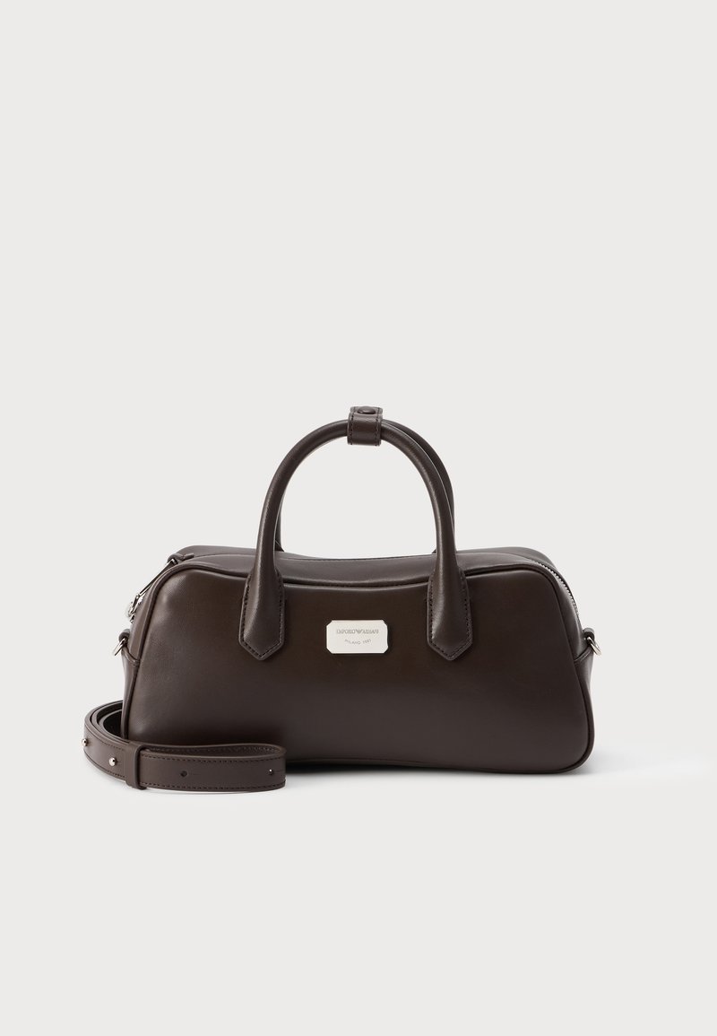 Sac à main en cuir marron foncé avec deux poignées, une bandoulière amovible et une petite plaque de marque rectangulaire argentée à l'avant.