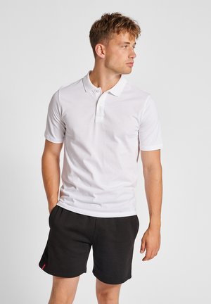 White cotton polo shirt with short sleeves, flat collar, and three-button placket, paired with black shorts. Simple design, no patterns.