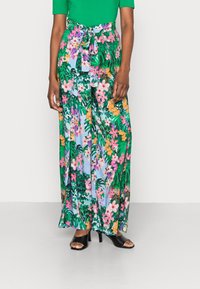 Pantalons maxi floraux verts, ornés de fleurs roses et orange et de motifs feuillus, avec un détail de taille nouée et une silhouette fluide.