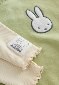 Zelena dukserica s bijelim motivom zeca, ribanim krem rukavima i oznakom s "Miffy" brendom. Mekana textura kroz cijeli komad.