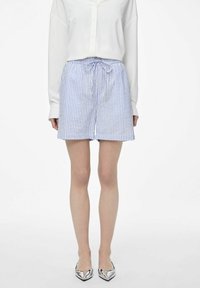 Shorts rayés en bleu et blanc, fabriqués en tissu léger, dotés d'une taille élastique avec cordon de serrage. Assortis à une chemise blanche à boutons.