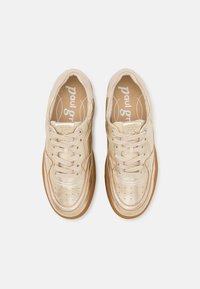 Goldfarbene Leder-Sneaker mit durchbrochenen Akzenten, runder Zehenpartie, flacher, honigfarbener Sohle und hellen Schnürsenkeln. Das Innere zeigt ein Logo-Design.