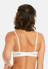 Soutien-gorge en dentelle blanche avec des bretelles réglables, une fermeture à crochets et un fini texturé sur la bande. La vue de dos met en avant un riche détail en dentelle.