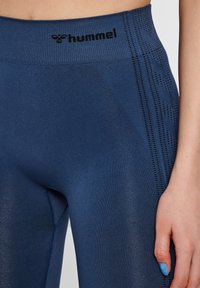 Námořnické modré sportovní legíny vyrobené z pružného materiálu, s ribbovaným pasem a bočními detaily s perforovanými vzory.