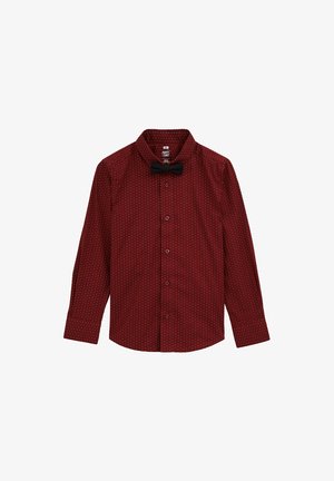 Red, long-sleeve button-up shirt with white polka dots and a black bow tie at the collar. Smooth texture, classic fit, and structured design.